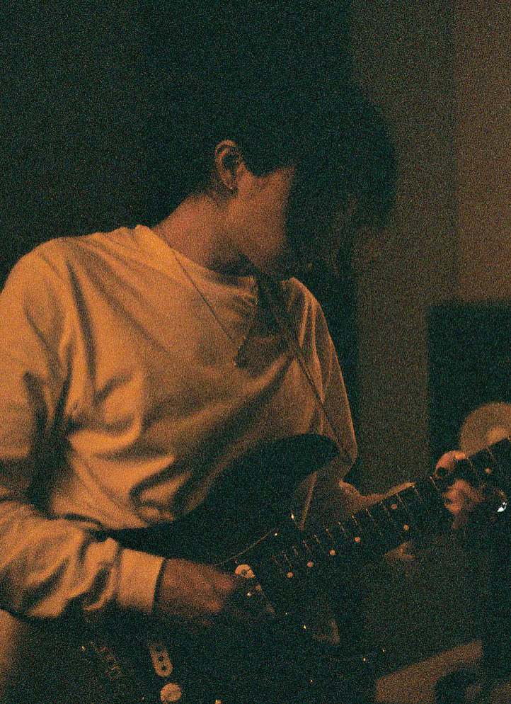 A grainy image of keshi playing a guitar.