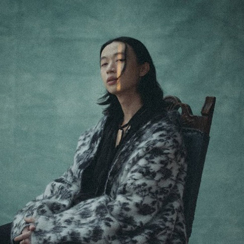 Thumbnail image for keshi's song 'TOUCH'. Depicts keshi sitting on a chair with a dull green background.